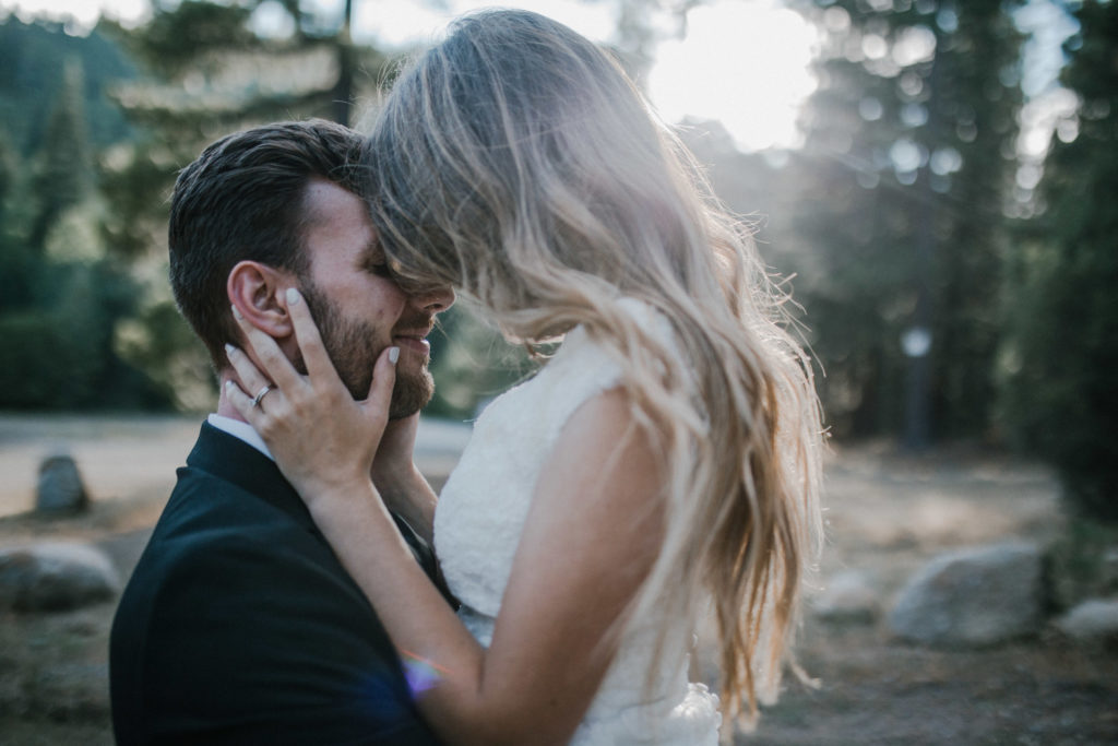 groom pikcing up bride and holding her with their foreheads touching in the woods with bright light. Forest wedding elopement.