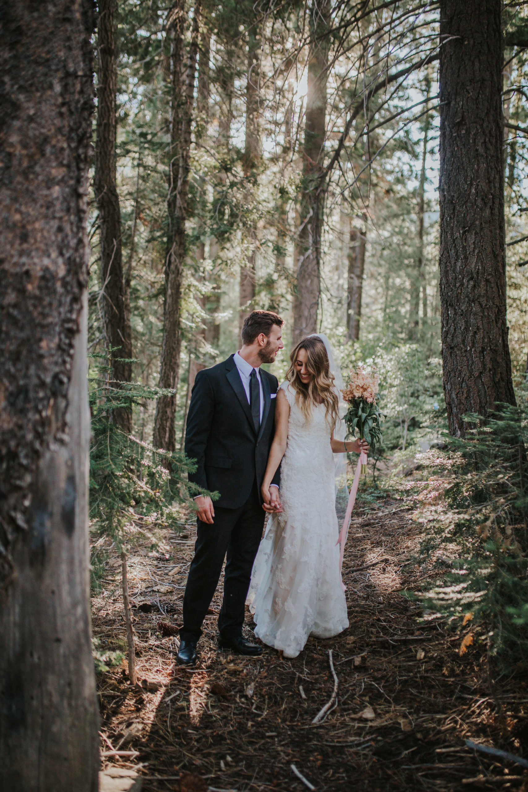 bride and groom holding hands and standing in the woods