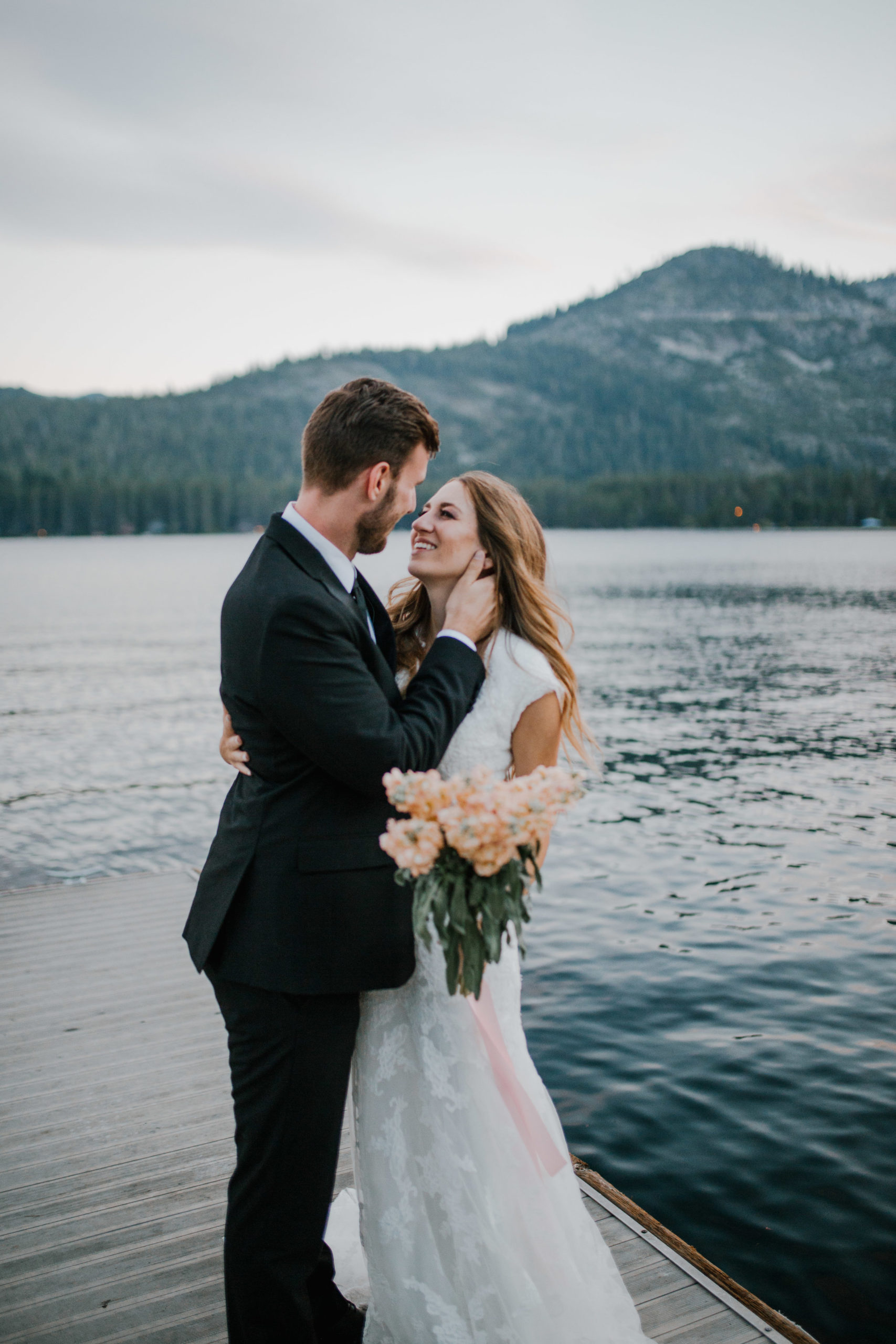 Sacramento wedding photographer captures bride and groom on a dock in the middle of a lake in Tennessee at sunset as the groom embraces the bride