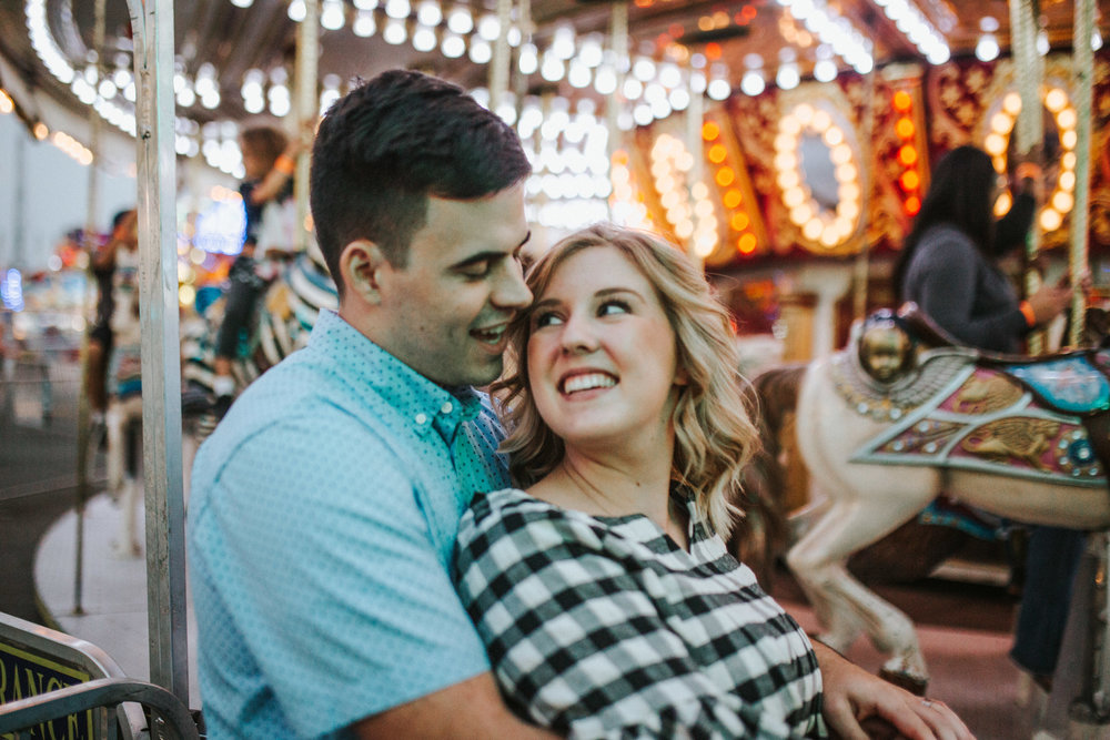 fun carnival engagement session with man holding woman on a carasol a