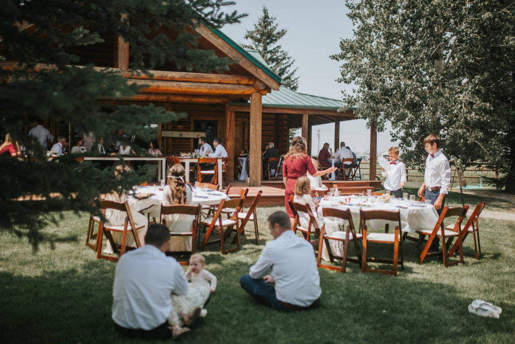 outdoor reception space in the Smoky Mountains with chairs and tables set up and guests hanging out in the shade for a summer wedding