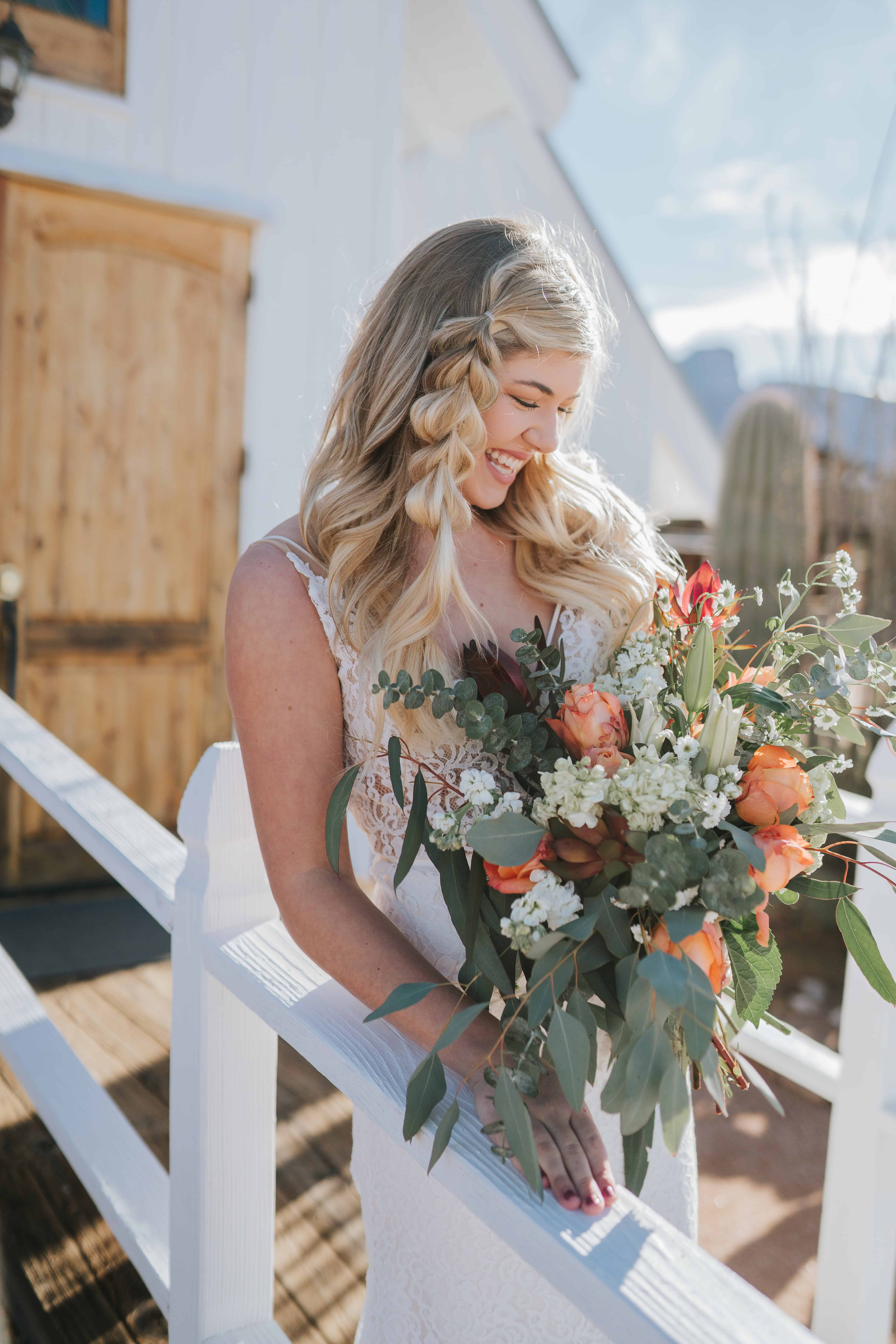 bride smiling down at her floral arrangement made up of colorful flowers