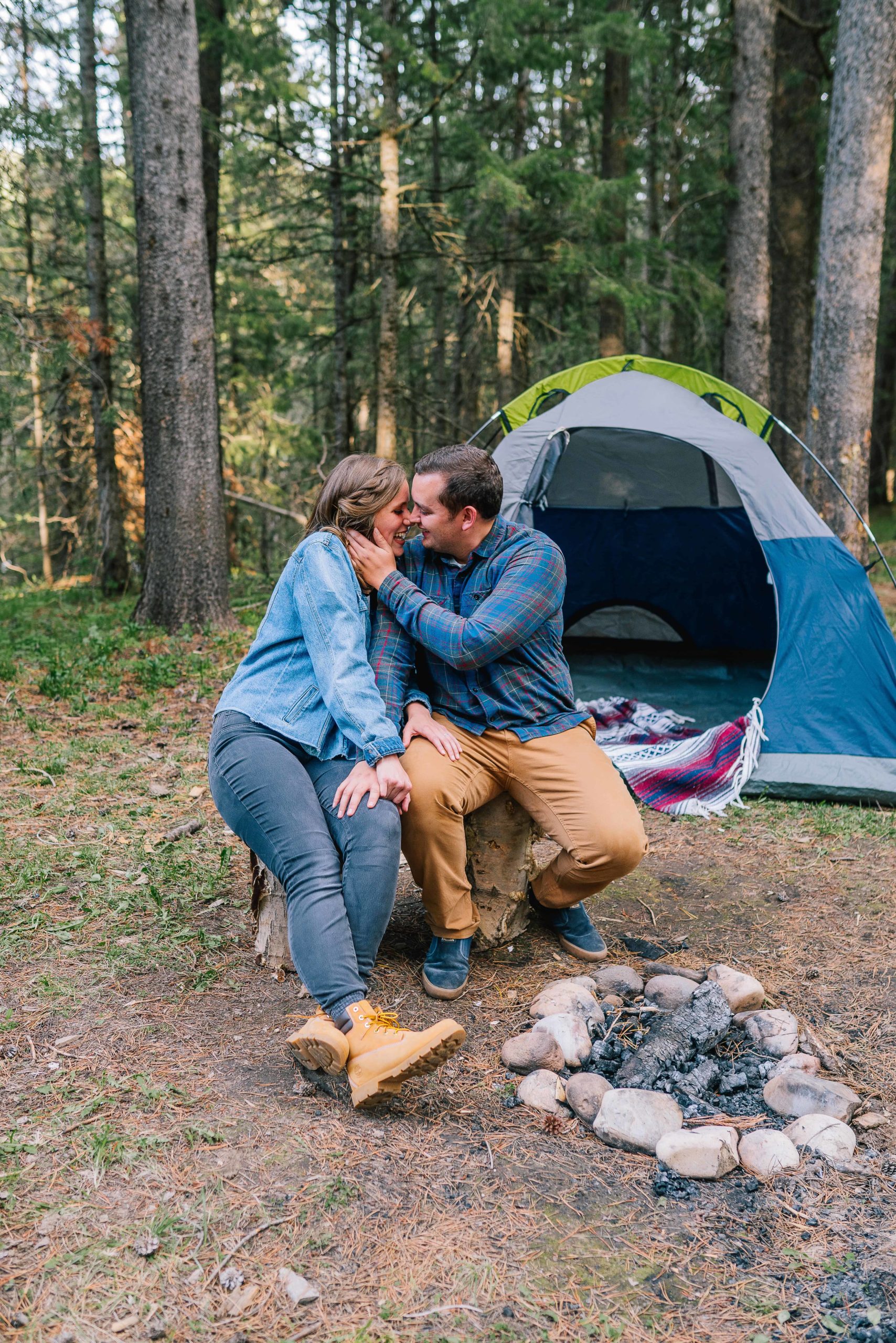 smoky mountain engagement session while camping. couple is kissing in front of the camp fire and tent behind them
