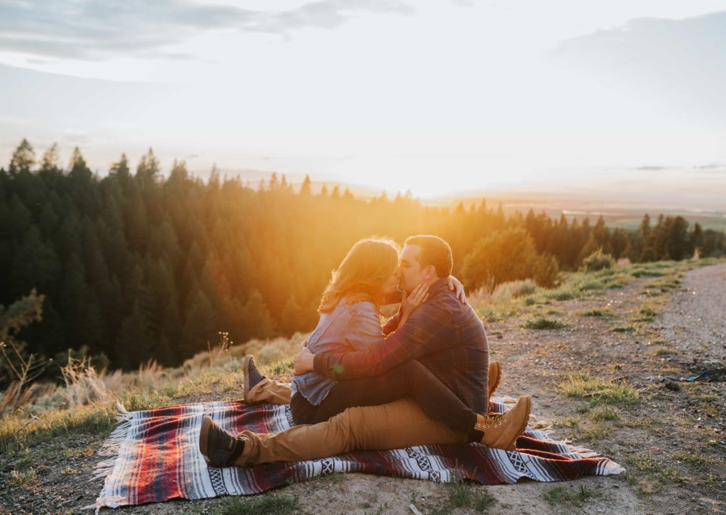 couple kissing each other at sunset on top of a mountain in the Smokies in Tennessee on a blanket during an engagement session