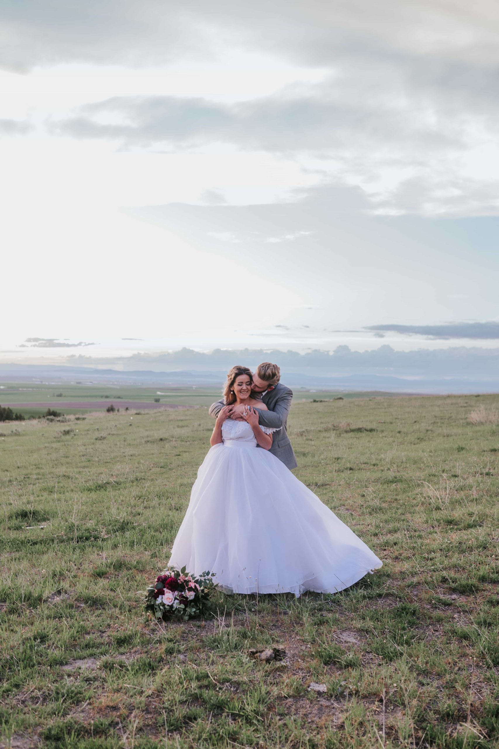 Bride and Groom holding each other in a field on top of a mountain