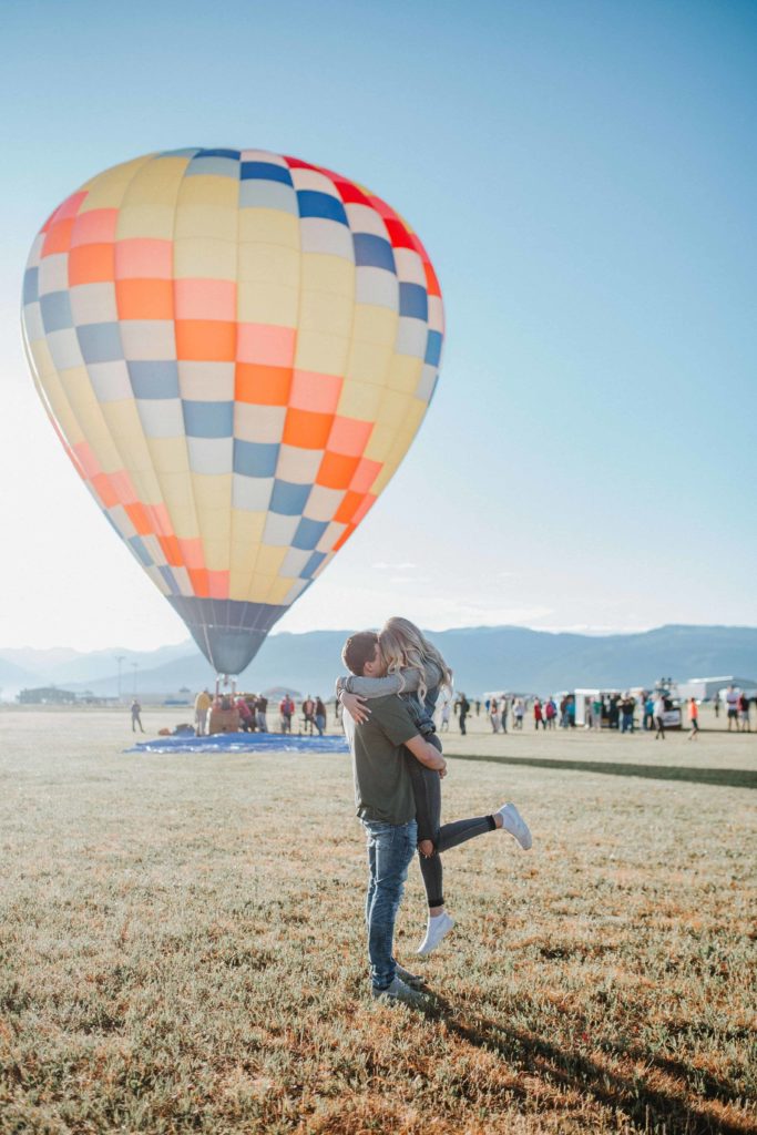 engagement session with hot air balloons. guy picking up the girl and hugging each other romantically. Located in Koxvegas 