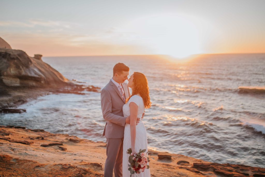 adventure session with bride and groom in Big Sur exploring and standing in front of the water and waves as the sunset in the background