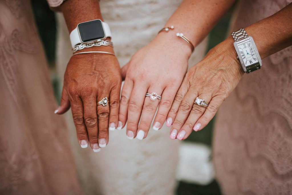 Three female hands with engagement and wedding bands on them