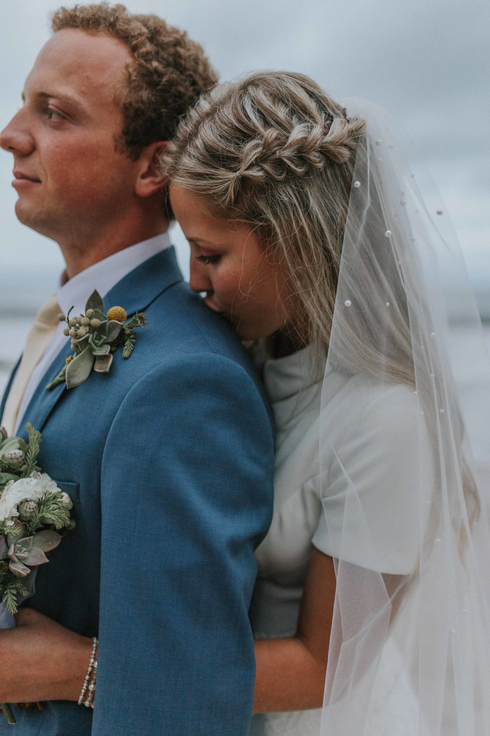 bride kissing groom's shoulder during beachy bridals in outer banks