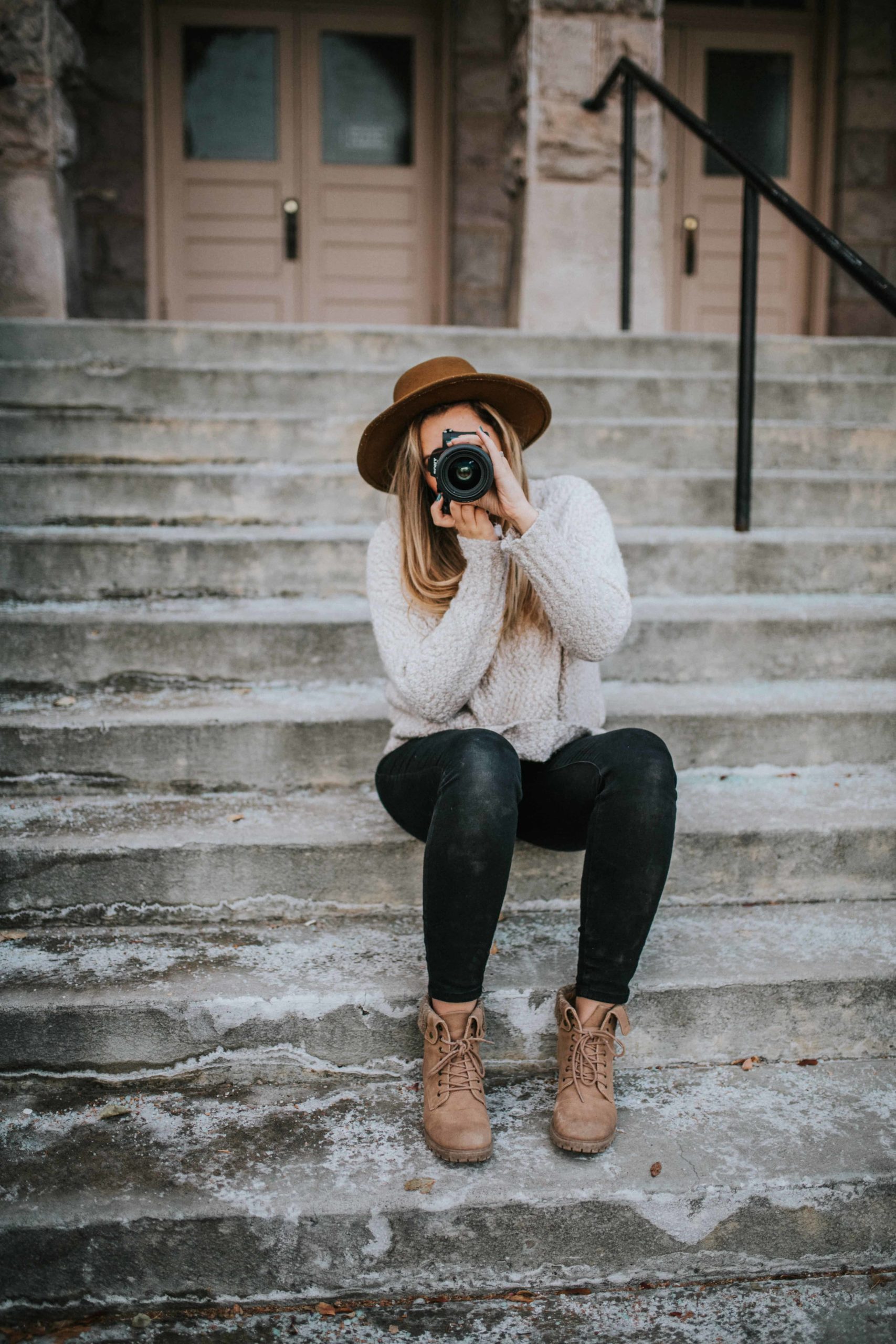 woman looking through a camera while sitting on steps in downtown knoxville learning about how to grow instagram following