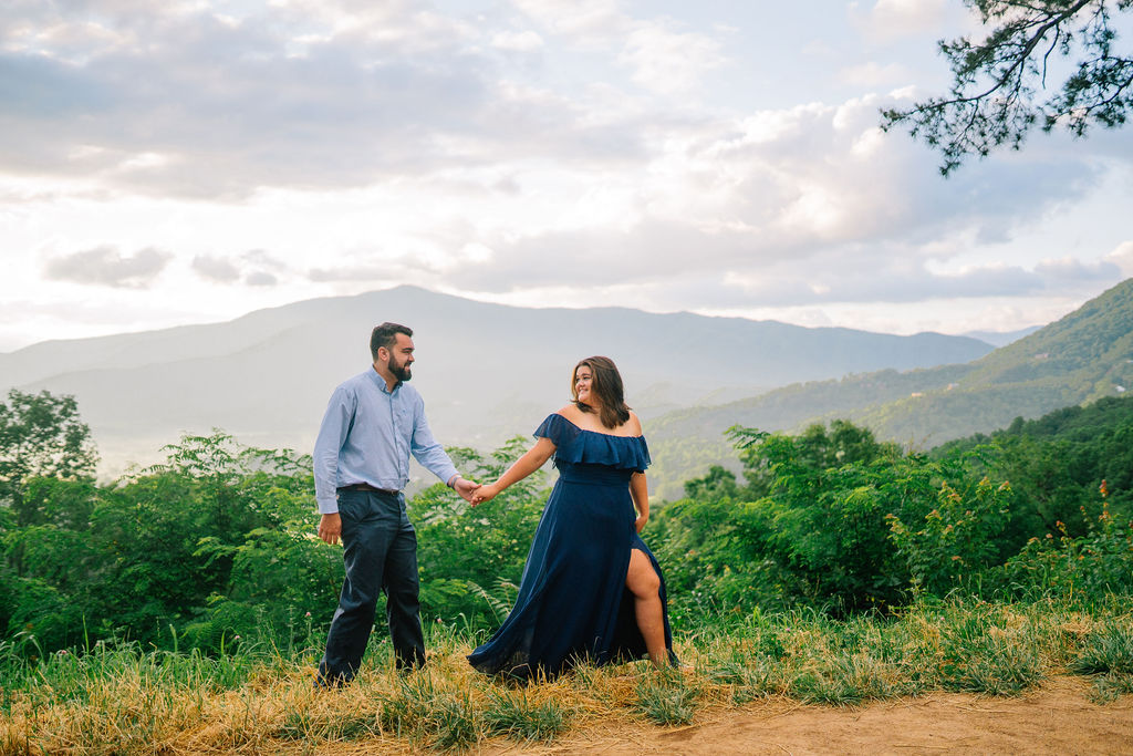 man and woman walking on a mountain in knoxville during engagement session at sunset