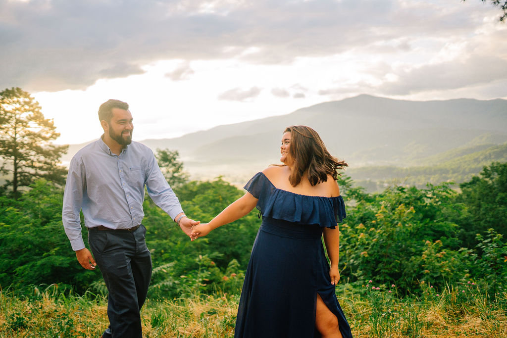 couple in the Smoky Mountains holding hands and smiling at each other while walking together in the forest