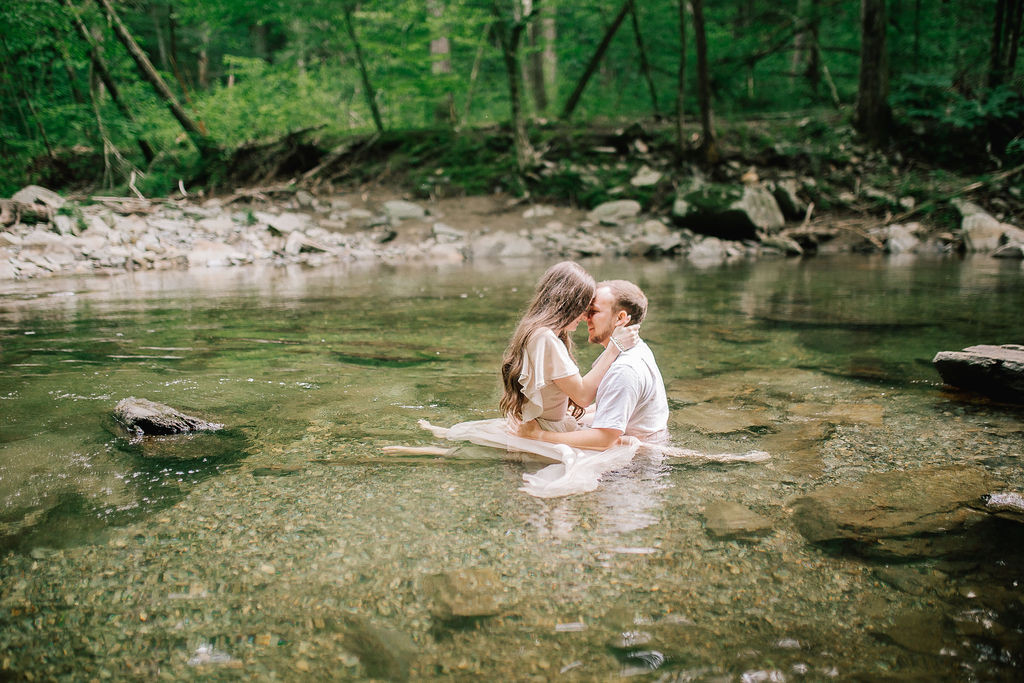 bride and groom in the water of a stream romantically holding each other
