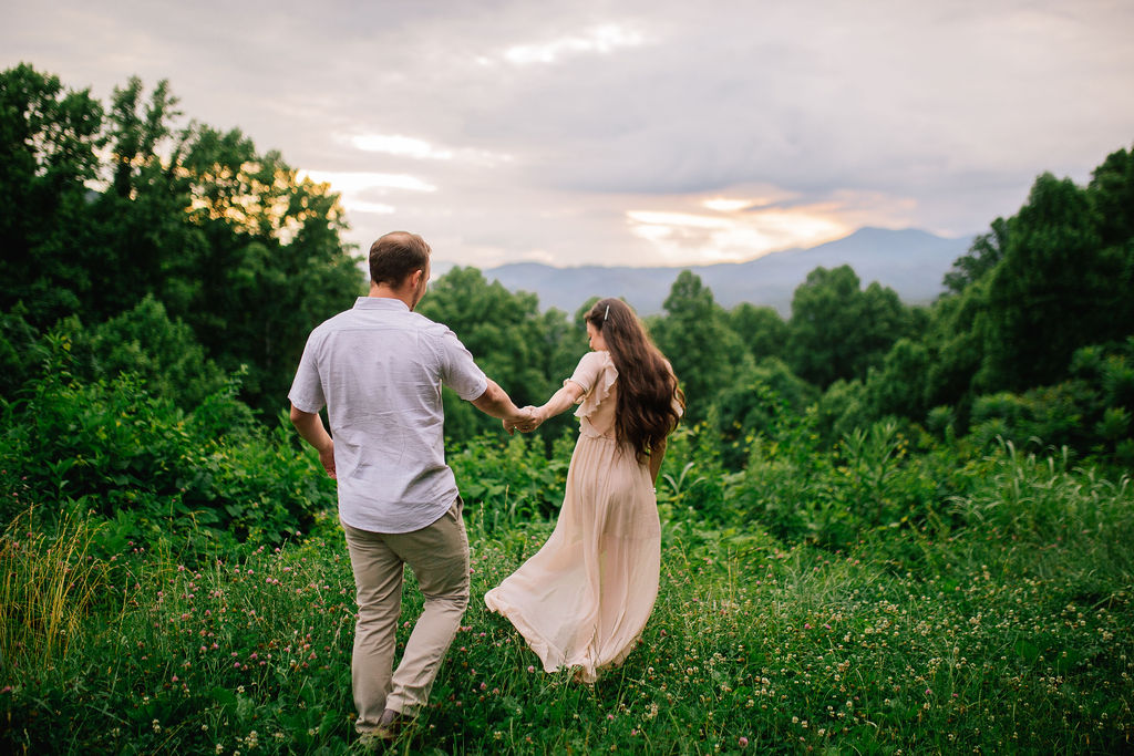 couple holding hands as the bride leads the groom into a green lush forrest in the Smoky Mountains 