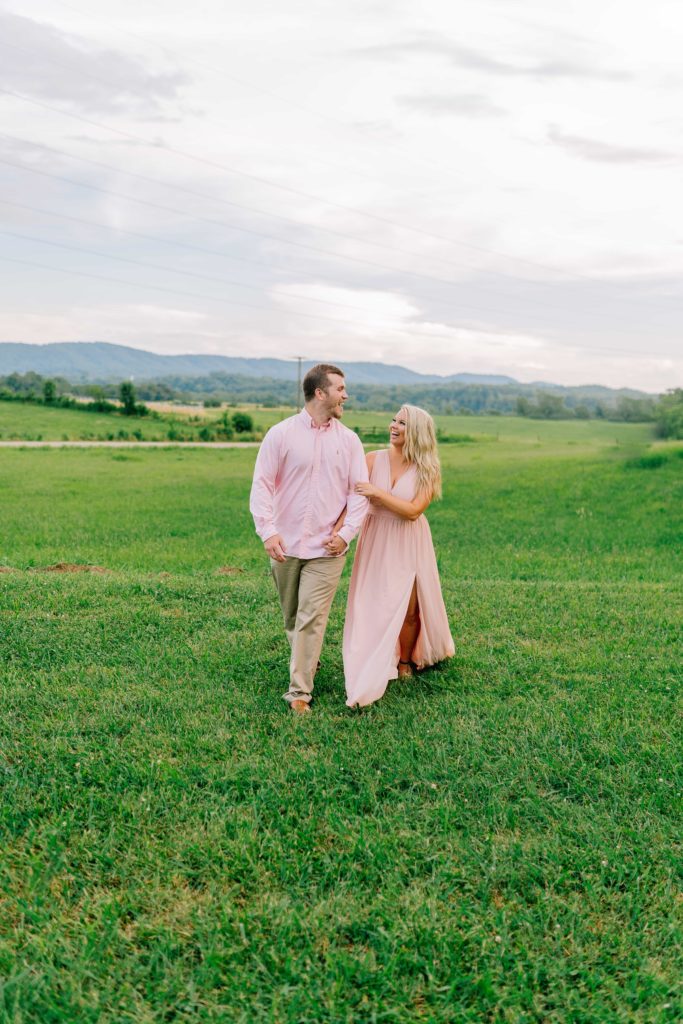 man and woman walking through tennessee field during engagement session after dreamy proposal