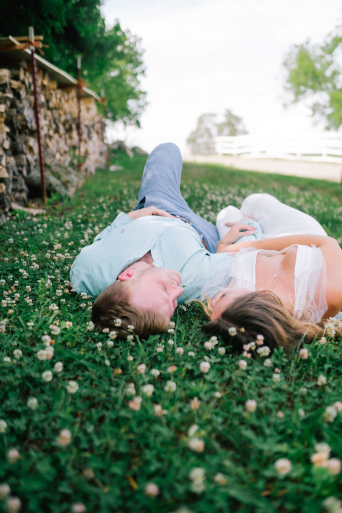 bride and groom laying on the grass with each other and staring at each other romantically.