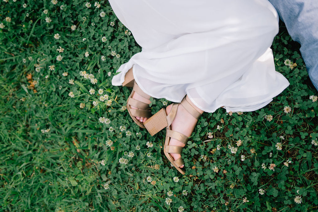 detail shot of the brides shoes against the grass with tiny flowers