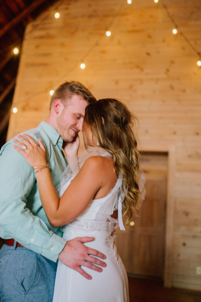 bride and groom dancing together in the barn at Marblegate Farm in Knoxville Tennessee. Wood shiplap walls and twinkle lights in this wedding venue.