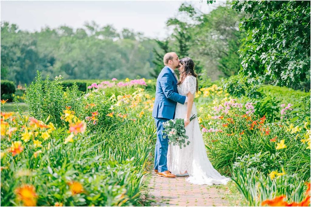 bride and groom standing in a gorgeous garden in Boston holding each other in the middle of a path in the bright and greengarden