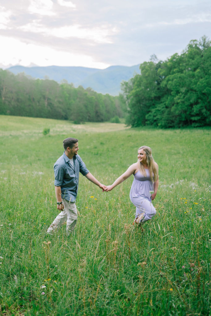 Cade's Cove engagement session holding hands through a field