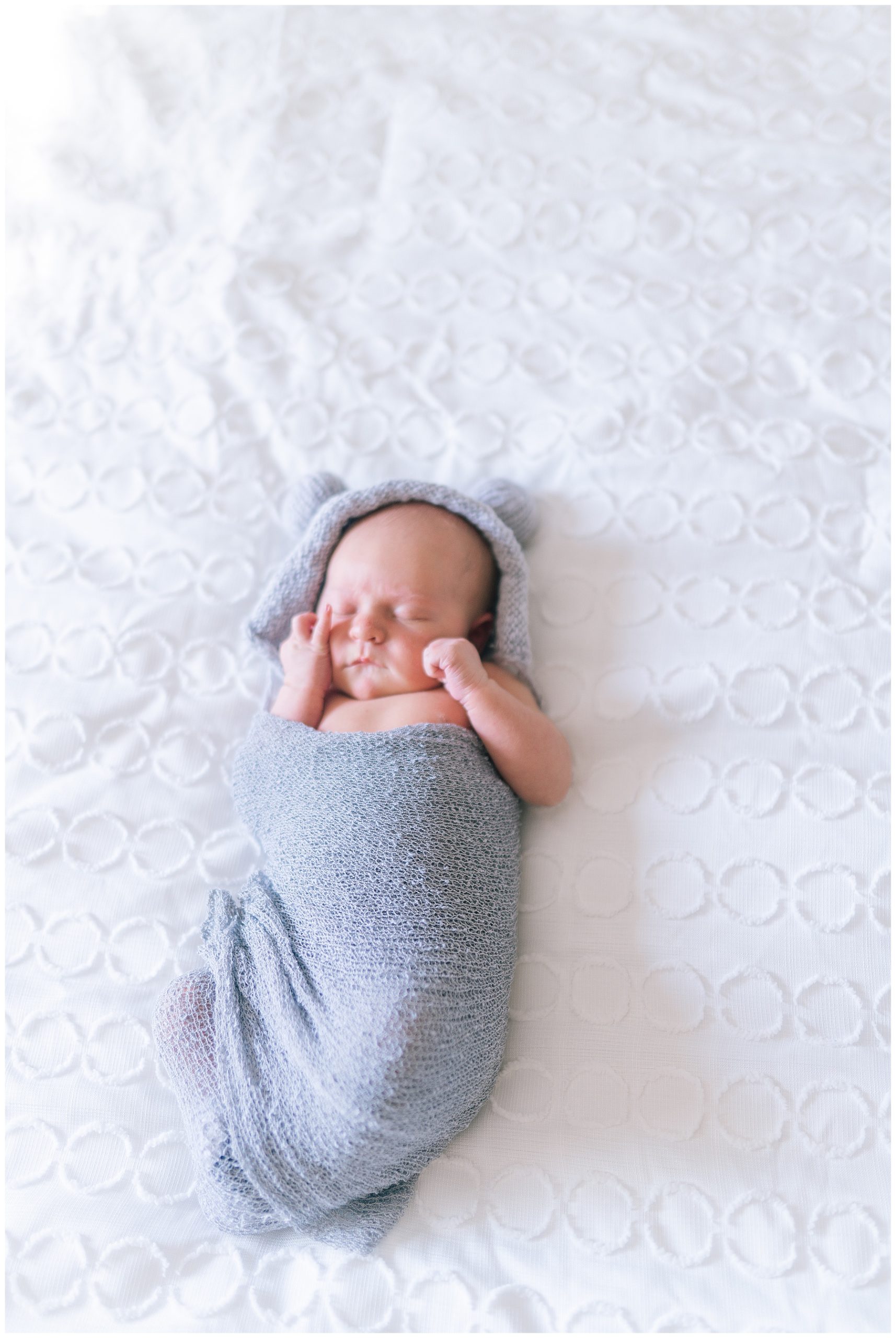 baby laying a a bed for a newborn shoot in a warm swaddle in Knoxville Tennessee