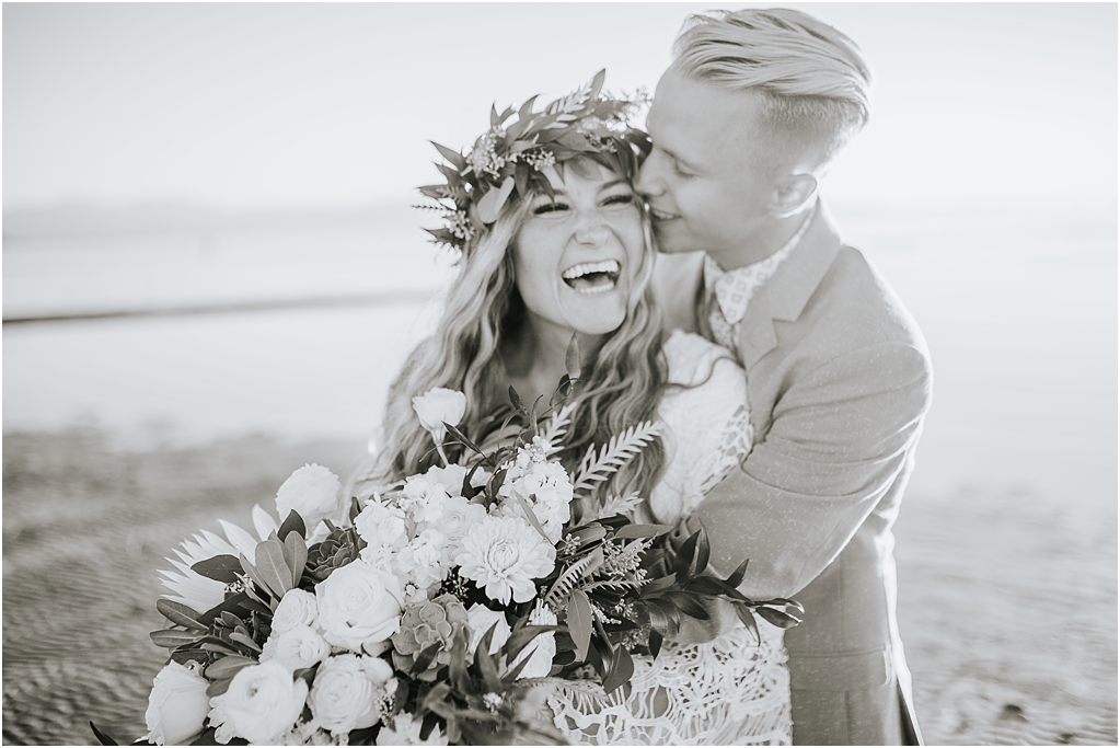 black and white wedding photography with bride and groom embracing and laughing together 