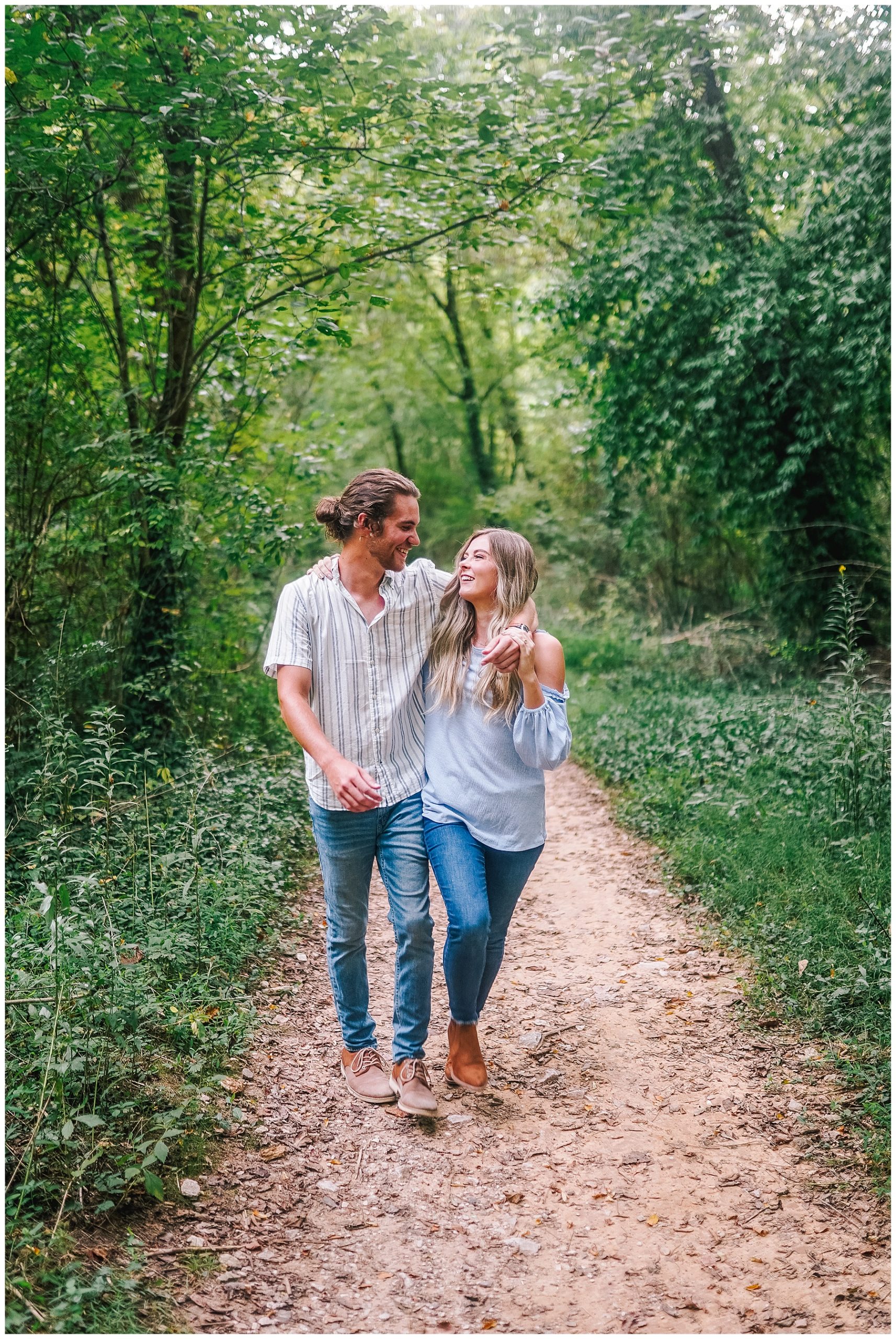 happy couple walking through a wooded forest in the Smoky Mountains with the mans arm around the girl