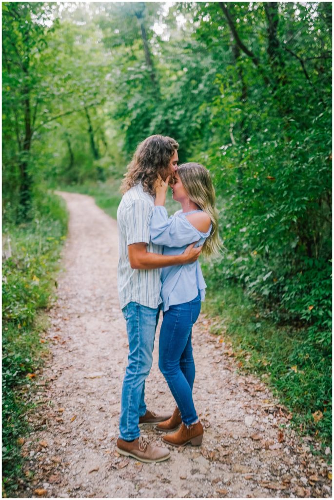 engaged couple standing on a trail in the ijams holding each other