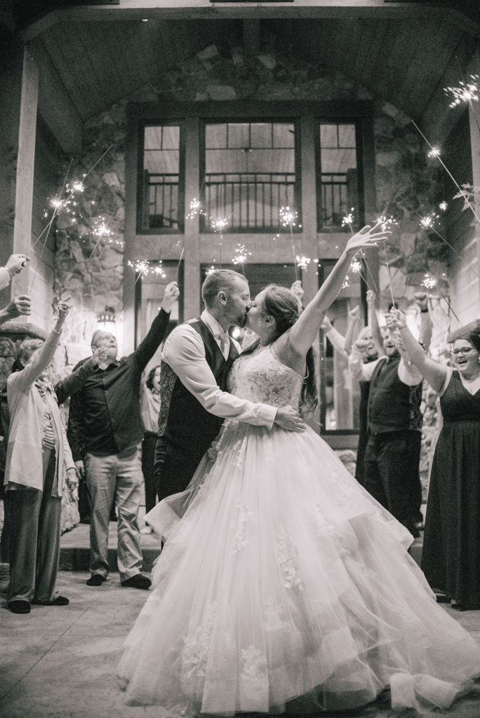 sending off the bride and groom by sparklers in front of a stone castle. black and white photo