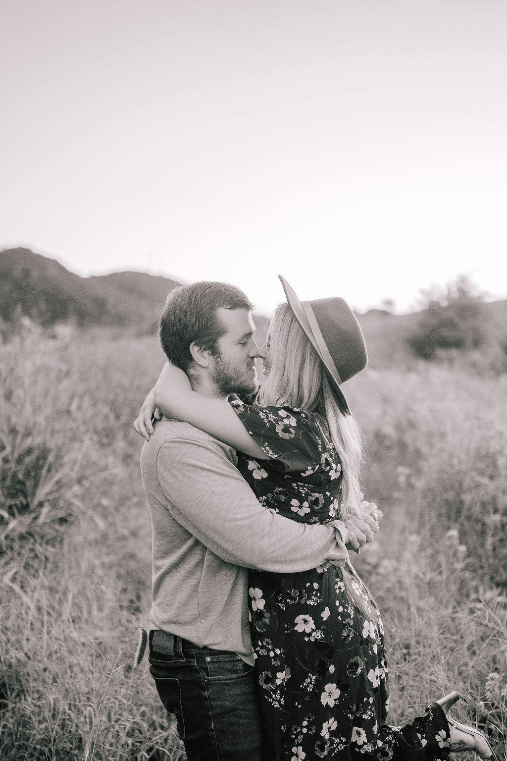 man and woman hugging and lifting woman up in knoxville field during engagement session