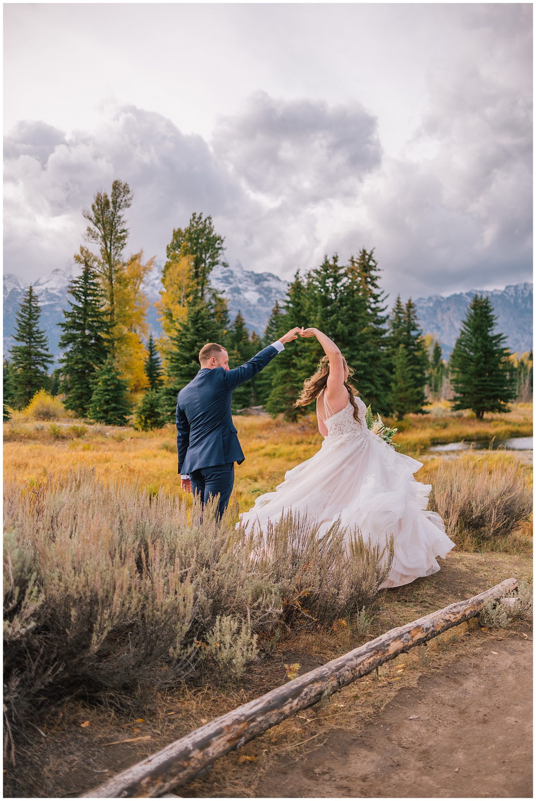 groom twirling his bride in the tetons as her dress flows through the yellow flowers