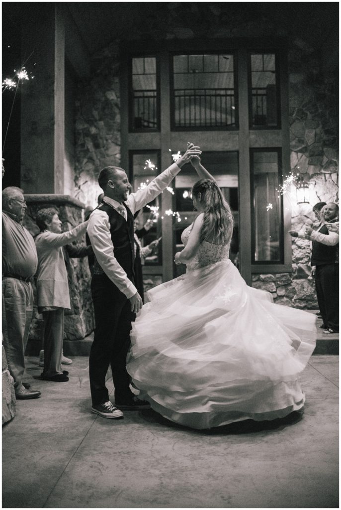 black and white photo of a bride twirling in her fluffy ballgown at the send off