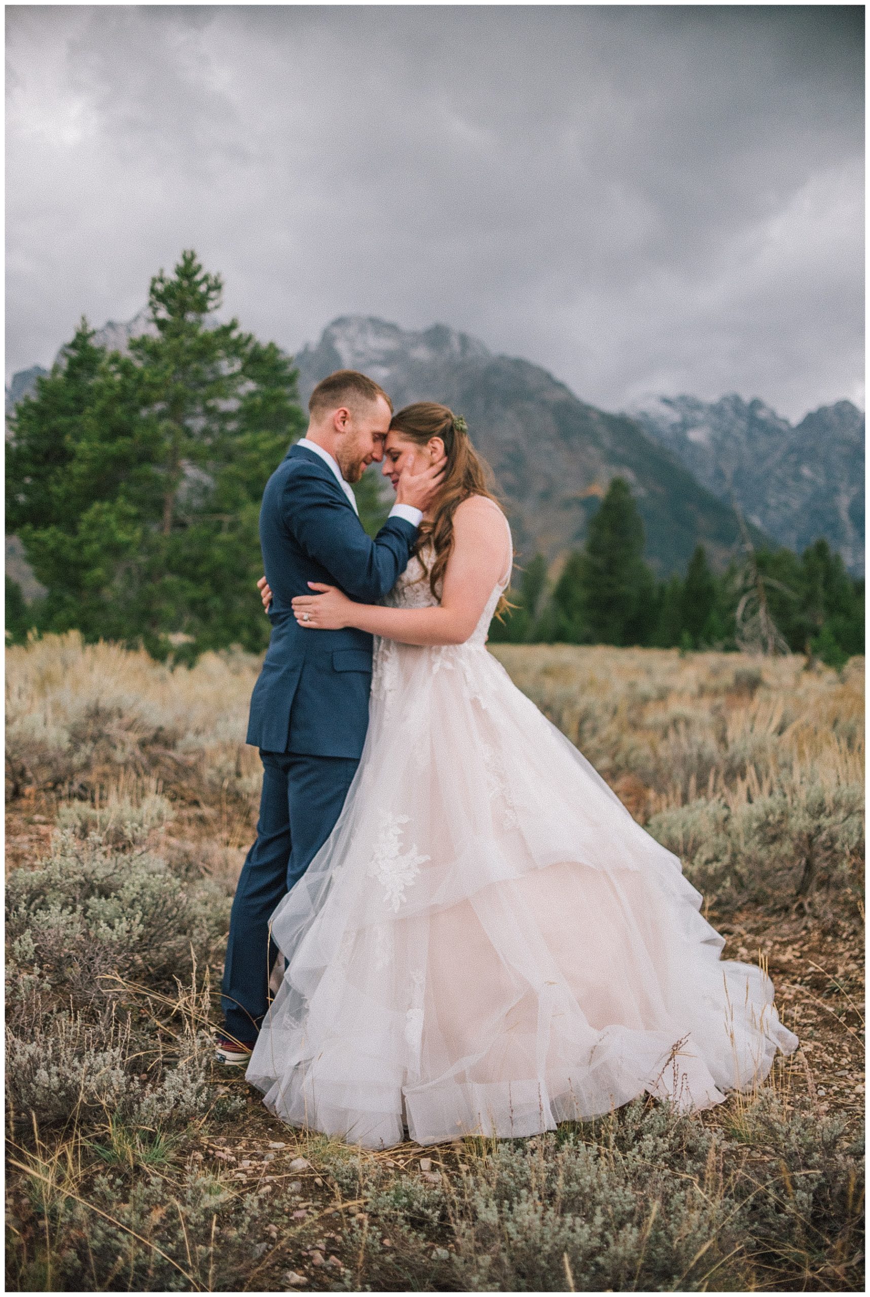 smoky mountain bride in a gloomy field holding her husband in front of mountains