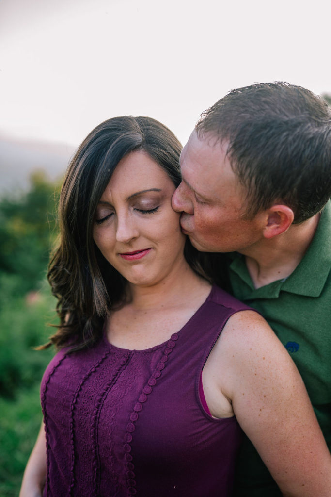 husband kissing the wife on the cheek as she has her eyes in the Foothills Parkway