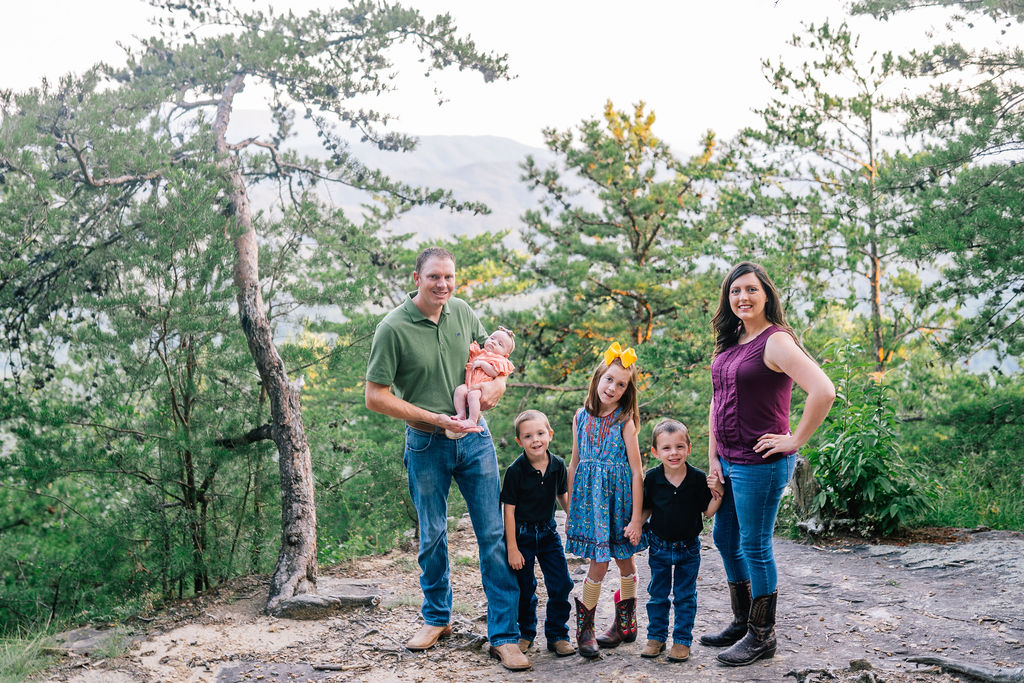 beautiful family posing in the Smokies along a tree line in the Foothills