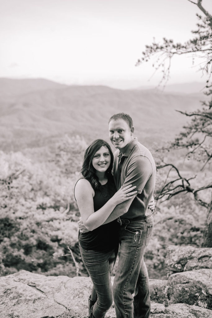 black and white picture of a married couple holding each other on a cliff in the Smokey Mountains