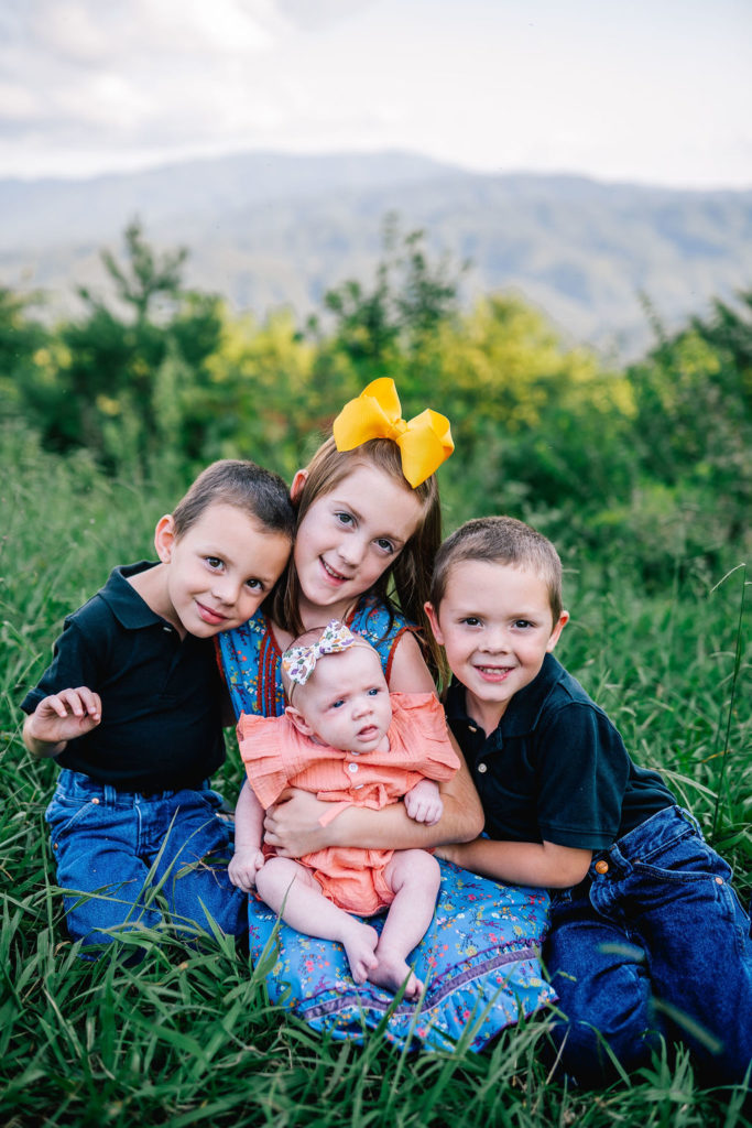 brother and sisters cuddled up together in the grass posing at the foothills parkway in Tennessee