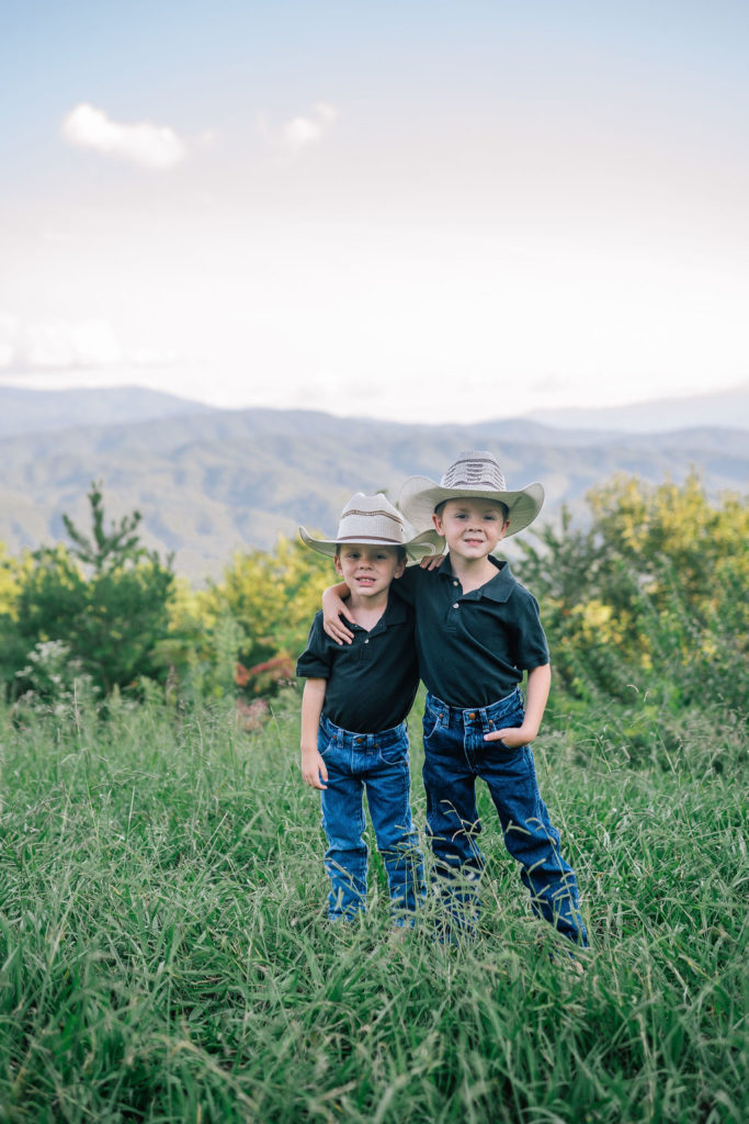 two child brothers with their arms around each other while wearing cowboy hats in the Smokey Mountains