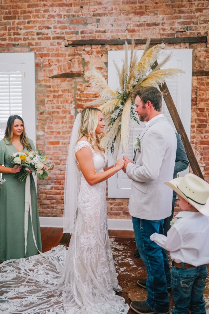 bride and groom standing at a bohemian themed triangle arch on their wedding day in Louisiana.