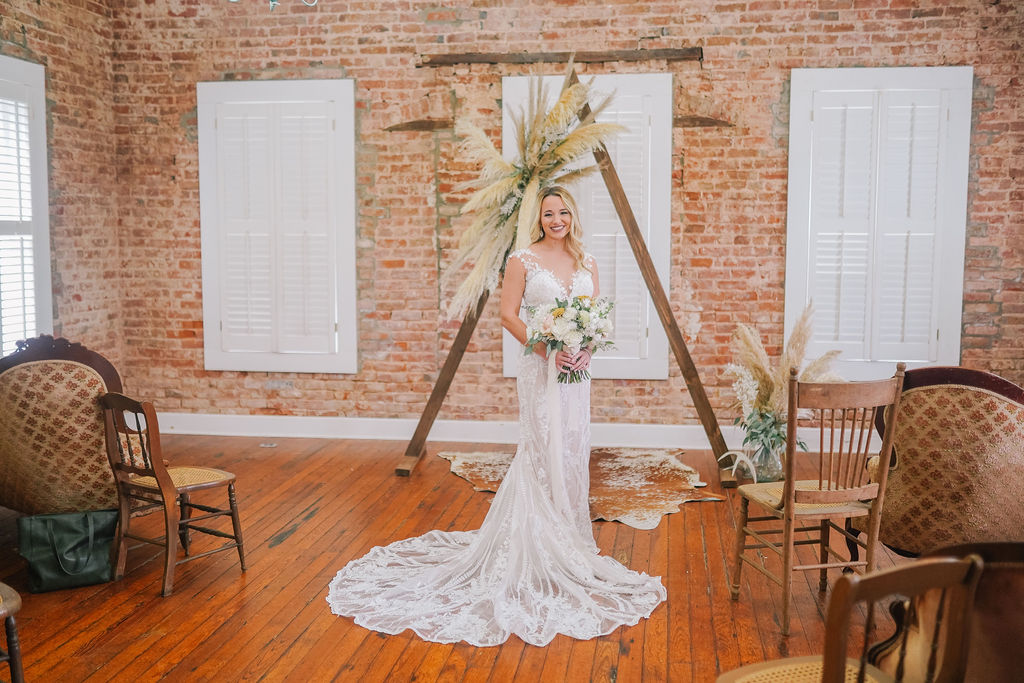 Bride standing in front of the alter in her wedding dress with her bouquet of flowers