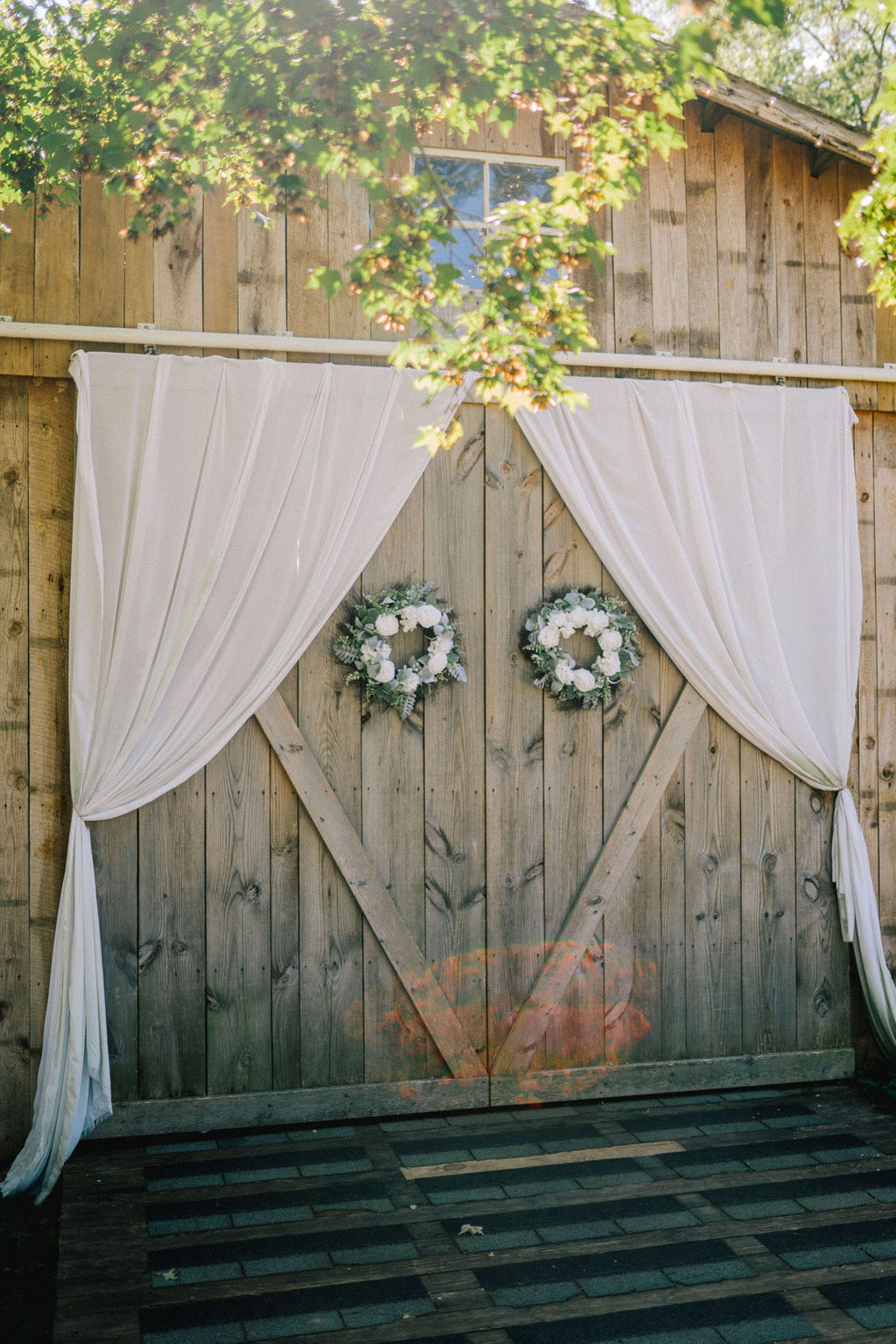 Decorated barn entrance with white curtains and flower wreaths