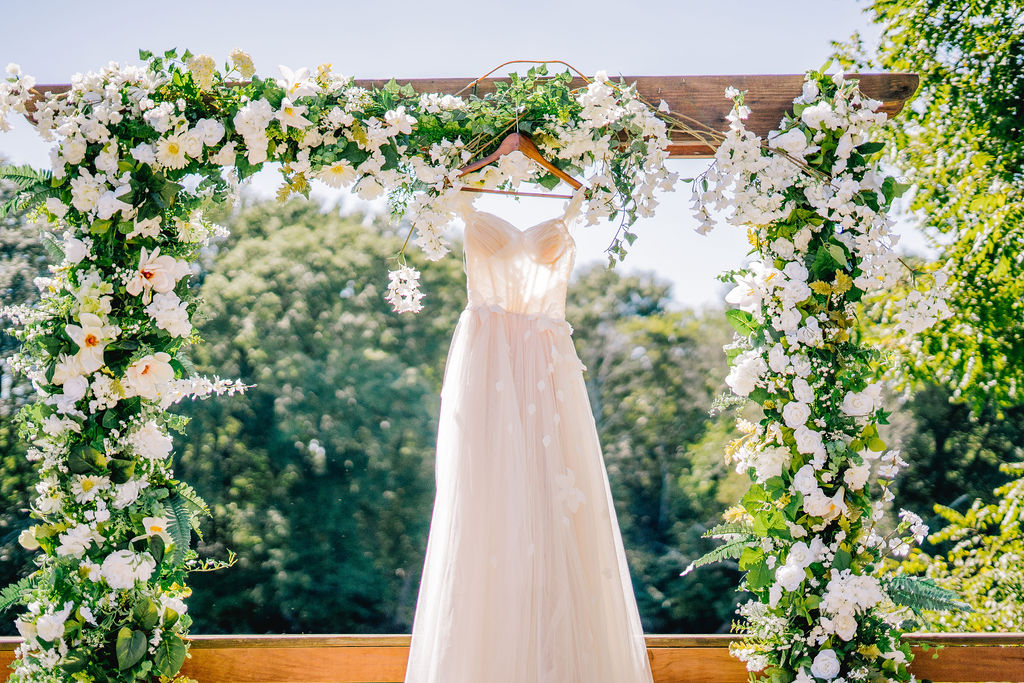 Lacy and flowery wedding dress hanging from wedding arch in Knoxville wedding