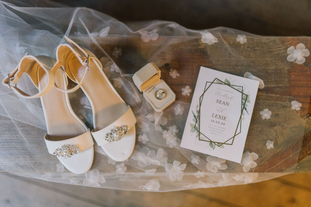 gorgeous flatlay with the brides veil, wedding shoes and invitation on wooden table