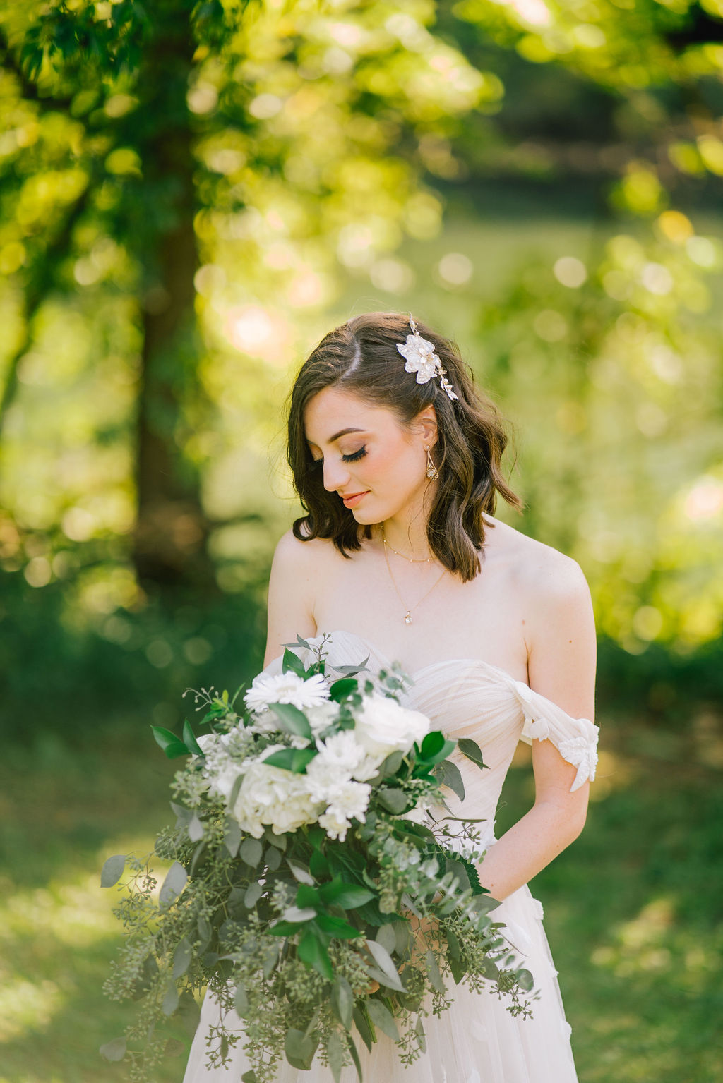 Bride outside while looking down at her bouquet of green and white flowers