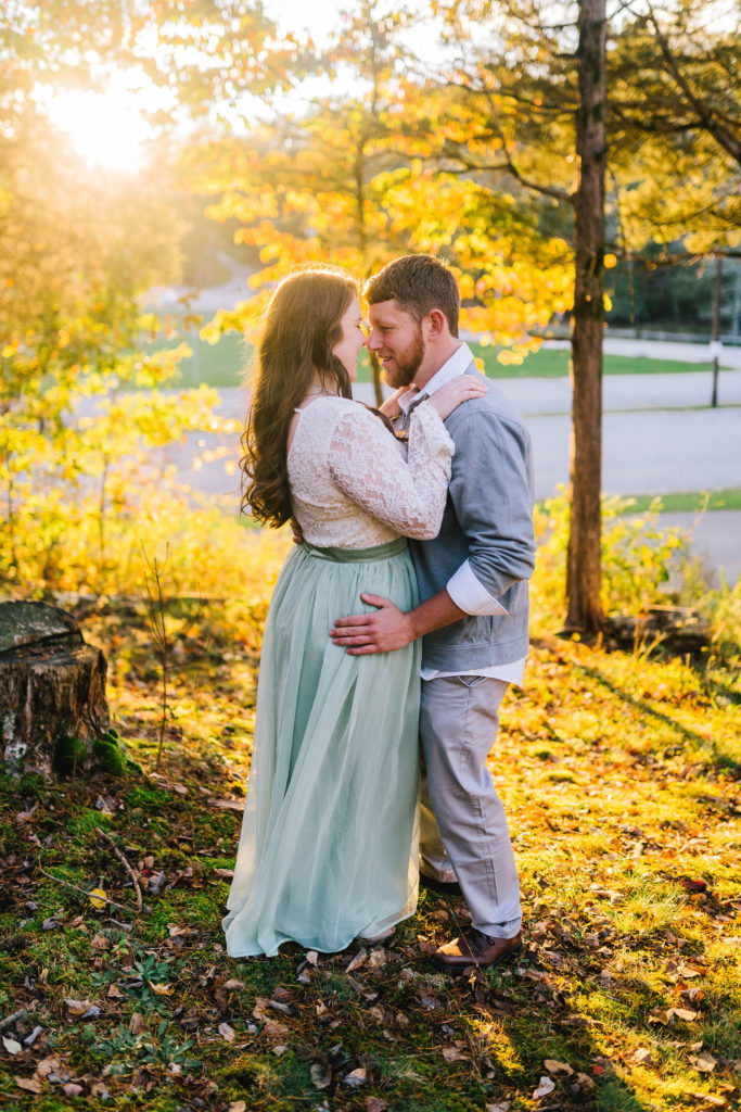 engagement session in Norris Lake in the fall with bright trees and water surrounding the couple.