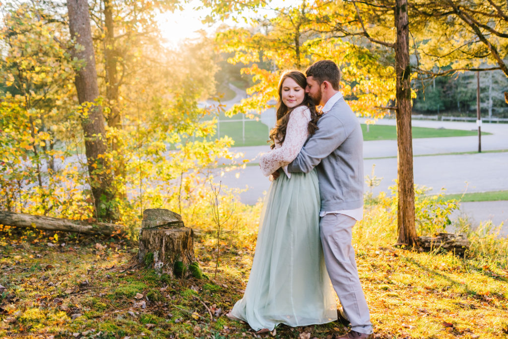 bright yellow fall trees in Tennessee with an engaged couple holding each other romantically.