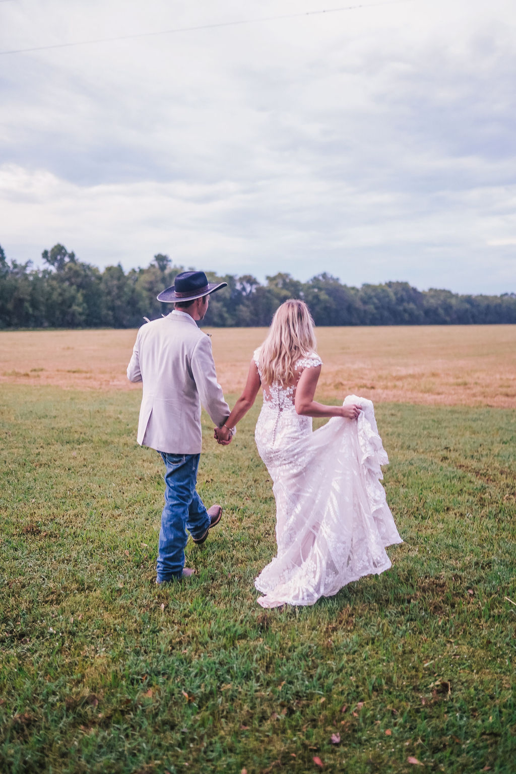 bride and groom walking off together in louisiana field during bridals session