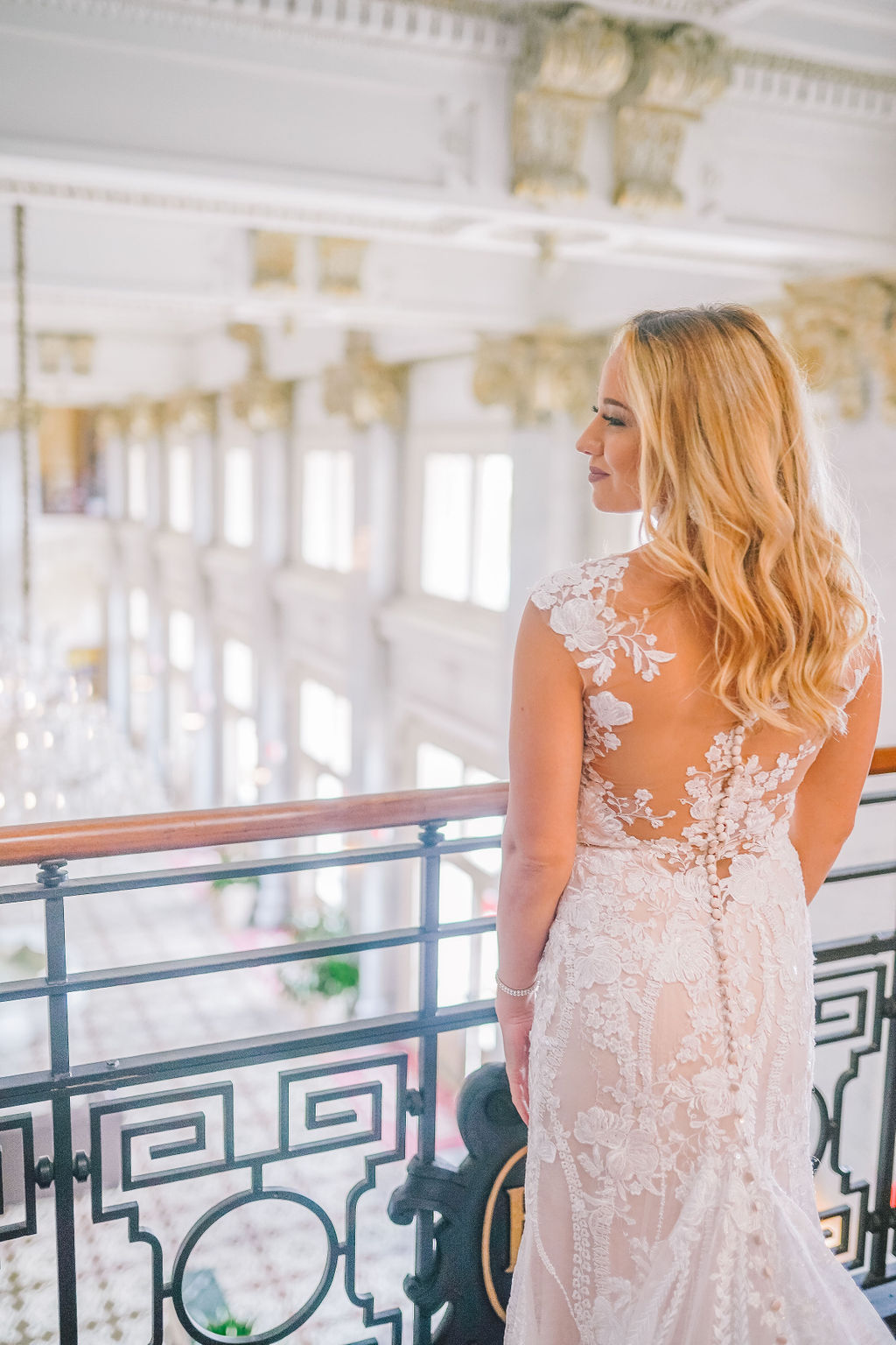 back of bride and her dress as she stands by a balcony
