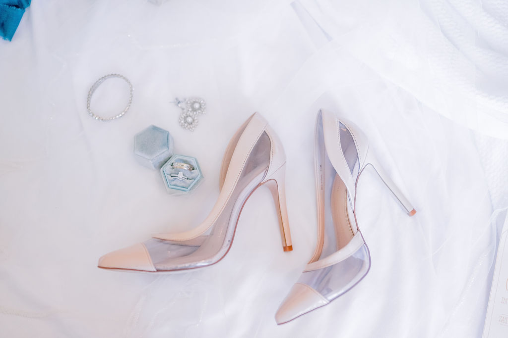 bridal wedding flatlay with brides soft pink pointed toe shoes and her wedding day jewelry 