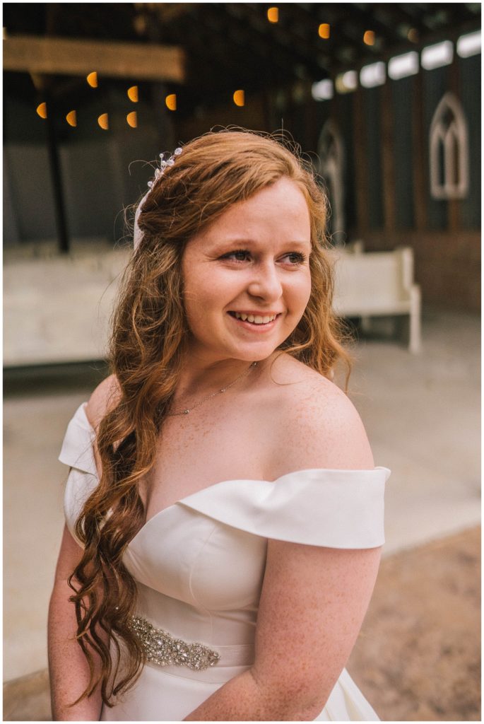 bride with long beautiful red hair smiling in the distance blushing with excitement on wedding day in knoxville